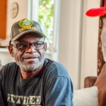 Two men talking, one wears a veteran hat.